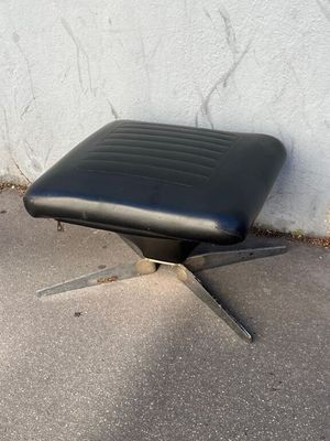 un fauteuil en cuir noir posé sur un sol en béton