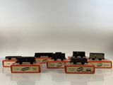 six toy trains are lined up in a row on a white surface