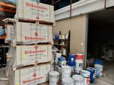 Plusieurs seaux de peinture sont empilés sur des palettes dans un garage