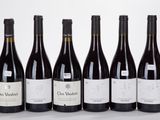 six bottles of wine are lined up in a row on a white surface