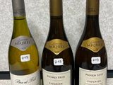 trois bouteilles de vin sont alignées sur un plan de travail
