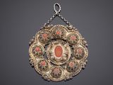 a close up of a necklace with a red stone in the center