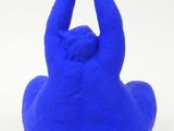 a blue sculpture of a person doing yoga on a white surface