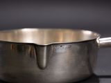 a silver saucepan with a handle on a black surface