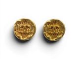 une paire de boucles d'oreilles en or sur une surface blanche