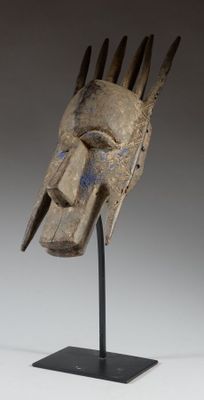 a close up of a wooden mask on a metal stand