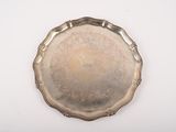 un plat en argent ancien posé sur une table blanche, sur fond blanc