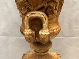 an antique cast iron vase on a pedestal with a white background