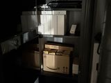 une porte ouverte donnant sur une petite pièce où se trouve une étagère remplie de cartons
