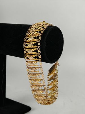 a close up of a gold bracelet on a black stand