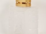 translucent glass perfume bottle with a gold lid on a white surface