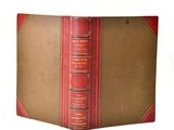 un vieux livre à la couverture rouge posé sur une table blanche