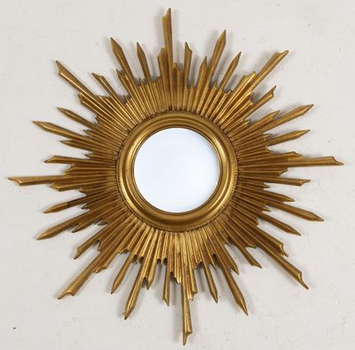 une photo d'un miroir doré en forme de soleil accroché au mur