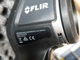 un gros plan sur une perceuse sans fil avec un téléphone portable en arrière-plan