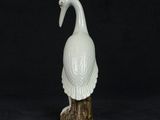 a white bird statue sitting on top of a wooden stump