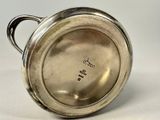 an image of a silver cup with a handle on a white surface