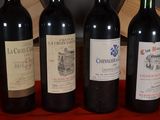 four bottles of wine are lined up on a red table cloth