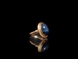 gros plan d'une bague en or avec une pierre bleue