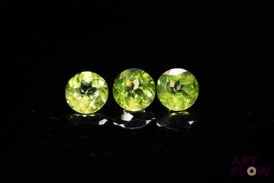a pair of green peridots sitting on top of a black surface