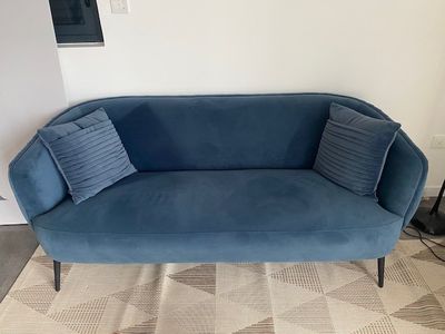 the couch is blue and has two pillows on top of it