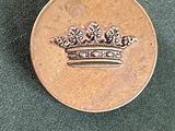 une pièce de monnaie sur laquelle est représentée une couronne, posée sur une table