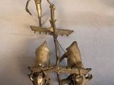 brass figurine of a man on a boat with birds on it