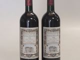 two bottles of red wine sitting next to each other on a table