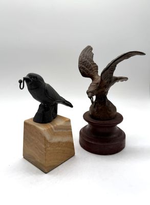 a statue of a bird on a pedestal next to a statue of a bird on a stand