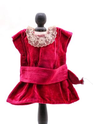 La robe est rouge et comporte un col en dentelle au niveau du cou.