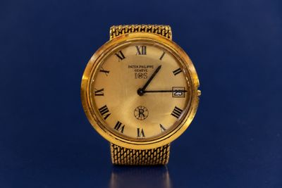 an image of a gold watch with roman numerals on a blue background