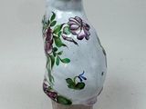 a white vase with purple flowers on it sitting on a table