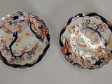 two plates with designs on them sitting on a white surface