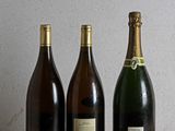 three bottles of wine are lined up on a wooden table