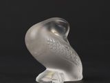 a glass bird that is sitting on a black surface