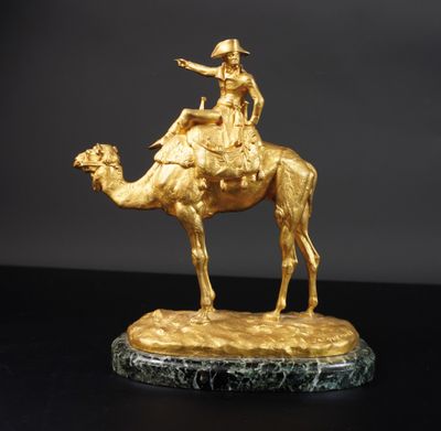 statue en or représentant un homme à dos de chameau, posée sur un socle en marbre