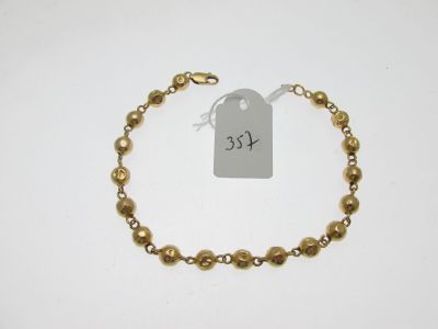 un bracelet en perles dorées sur lequel est accrochée une étiquette de prix
