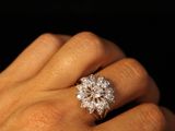 a woman ' s hand with a diamond ring on it ' s finger