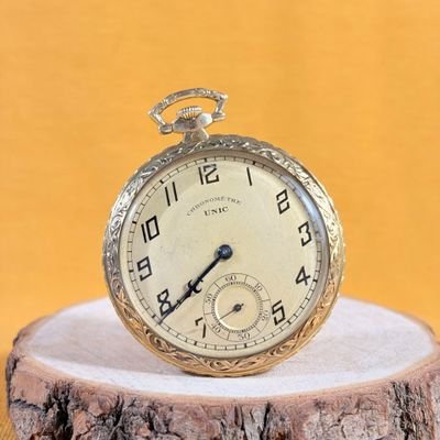 an old pocket watch sitting on top of a piece of wood