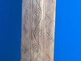 an old wooden carving of a bird on a stand against a blue wall