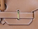 a close up of a brown leather bag with a metal handle