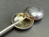 a metal strainer with a metal spoon in it