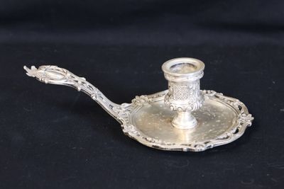 an antique silver plate with a candle holder on a black background