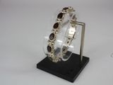 silver bracelet with garnetts on display on a black stand