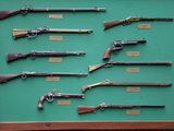 display of old guns displayed in a wooden frame on a green surface