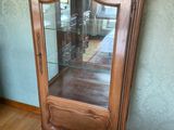 une armoire en bois avec une porte vitrée, placée dans un coin