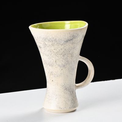 une tasse blanche et verte posée sur une table blanche