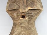 a close up of a wooden mask on a white surface