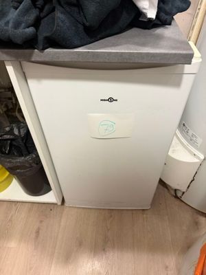 a white refrigerator with a bunch of clothes on top of it