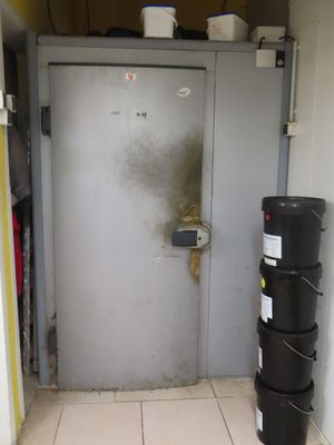 une poubelle noire posée devant une porte blanche