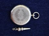 a silver pocket watch with a silver chain on a blue surface
